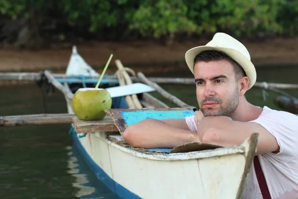 ボートと熱帯川でココナッツカクテルを持つハンサムな若い男のクローズアップ肖像画 — ストック写真