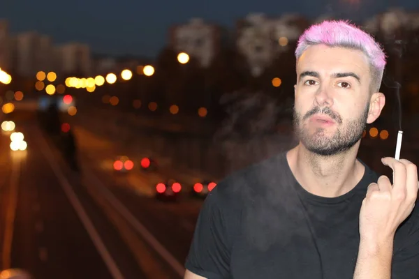 ピンク色の髪をしたハンサムな若い男が夜に路上で喫煙し — ストック写真