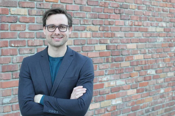 Tuğla duvarın önünde yakışıklı genç işadamının yakın plan çekimi.