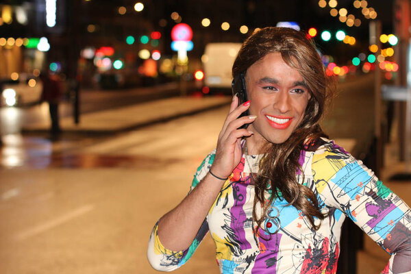 портрет трансгендерной женщины, разговаривающей по телефону на городской улице ночью