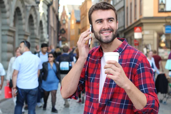 Sokakta elinde kağıt kahve olan yakışıklı bir gencin yakın plan portresi.