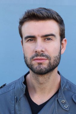 Duvarın önündeki yakışıklı sakallı adamın yakın plan portresi.