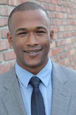 Yakışıklı Afro-Amerikan iş adamının yakın plan portresi tuğla duvarın önünde.