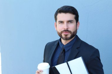 Elinde kahve fincanı ve klasörü olan bir iş adamı.