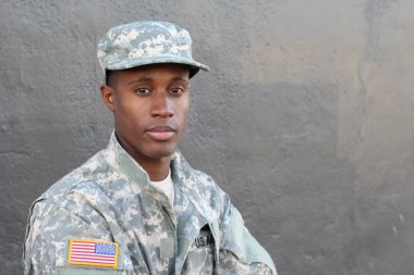 Gri duvarın önündeki yakışıklı Afro-Amerikan askerinin yakın plan portresi.