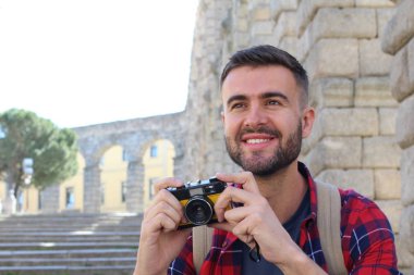 Yakışıklı bir gencin klasik bir kamerayla fotoğraf çektiği yakın plan portresi.