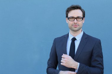 Mavi duvarın önünde genç ve yakışıklı iş adamının yakın plan çekimi.