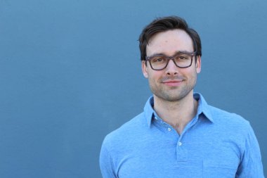 Mavi duvarın önünde sıradan giyinmiş yakışıklı bir gencin yakın plan portresi.