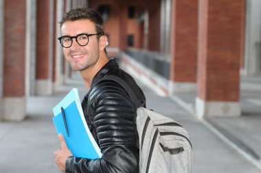 Şehir sokaklarında dosyasıyla günlük giysiler içinde yakışıklı bir gencin yakın plan portresi.
