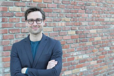 Tuğla duvarın önünde yakışıklı genç işadamının yakın plan çekimi.