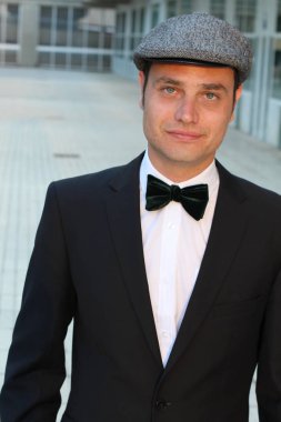 Siyah takım elbiseli, papyonlu ve şapkalı yakışıklı bir adamın yakın plan portresi.