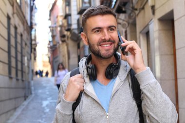 Eski şehir caddesinde telefonla konuşan yakışıklı bir gencin yakın plan portresi.