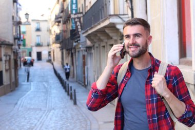Eski şehir caddesinde sırt çantalı yakışıklı bir gencin yakın plan portresi.