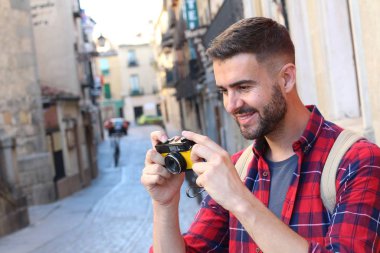 Eski şehir caddesinde, sırt çantalı yakışıklı bir gencin klasik film kamerasıyla çekilmiş yakın plan portresi.