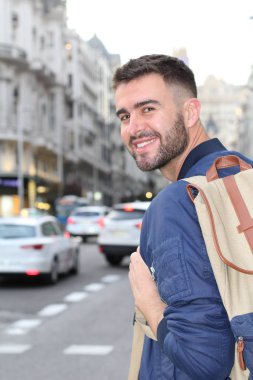 Şehir caddesinde sıradan kıyafetler giymiş yakışıklı bir gencin yakın plan portresi.