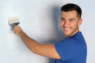 Neşeli etnik erkek evinde bir duvar boyamak üzere.