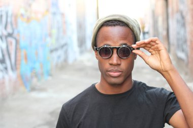 Sokakta siyah tişörtlü yakışıklı Afro-Amerikan adamın yakın plan portresi.