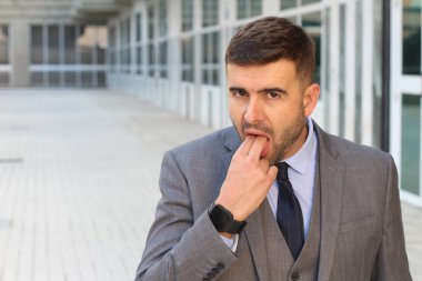 Yakışıklı genç işadamının yakın plan portresi. Sokakta iki parmağını ağzına soktu.