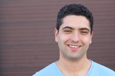 Kahverengi duvarın önündeki yakışıklı genç adamın yakın plan portresi.