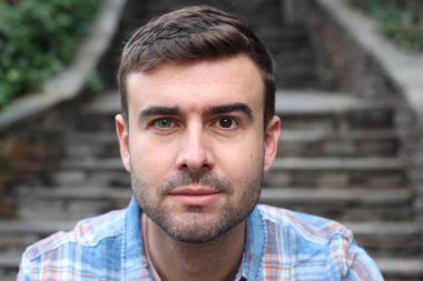 Şehir caddesinde sıradan kıyafetler giymiş yakışıklı bir gencin yakın plan portresi.