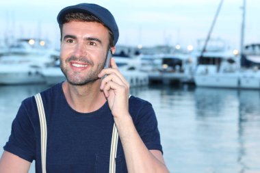 Limanda telefonla konuşan yakışıklı bir gencin yakın plan portresi.