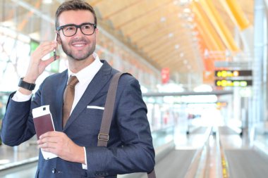 Yakışıklı, takım elbiseli, pasaportlu ve havaalanında uçuş bileti olan genç iş adamının yakın plan fotoğrafı.