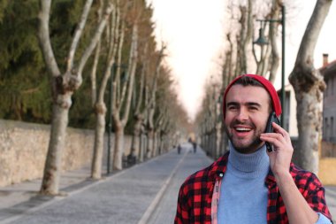 close-up portrait of handsome young man talking by phone on street