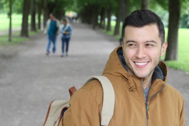Parkta gülümseyen kışlık kıyafetli moda bir erkek.
