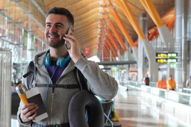 Genç bir adam havaalanından telefon alıyor.