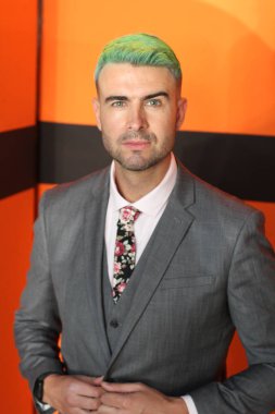 Turuncu arka planda duran yeşil saçlı zarif yakışıklı adam.