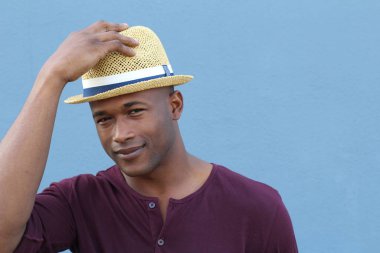 Mavi duvarın önünde şapkalı yakışıklı Afro-Amerikan bir adamın yakın plan portresi.