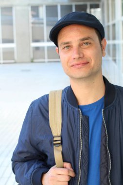 Yakından çekilmiş, sıradan kıyafetler giymiş ve şapkalı yakışıklı genç bir adam portresi.