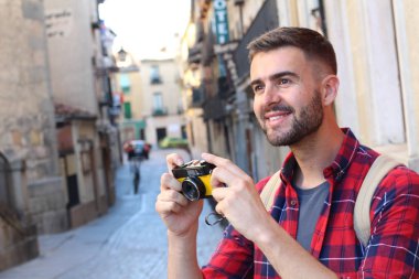 Eski şehir caddesinde sırt çantalı ve klasik kameralı yakışıklı bir gencin yakın plan portresi.