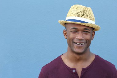 Mavi duvarın önünde şapkalı yakışıklı Afro-Amerikan bir adamın yakın plan portresi.