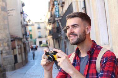 Eski şehir caddesinde sırt çantalı ve klasik kameralı yakışıklı bir gencin yakın plan portresi.