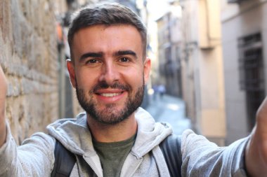 Eski şehrin sokaklarında selfie çeken yakışıklı bir gencin yakın plan portresi.