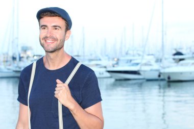 Gün batımında yatların önünde şık giyinmiş yakışıklı bir gencin yakın plan portresi. 