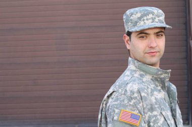close-up portrait of handsome young soldier in front of brown wall