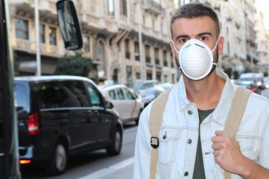 Sokakta tıbbi güvenlik maskesi takmış yakışıklı genç adamın yakın plan portresi.
