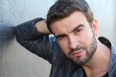 Duvarın önündeki yakışıklı sakallı adamın yakın plan portresi.