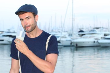 Gün batımında yatların önünde şık giyinmiş yakışıklı bir gencin yakın plan portresi. 