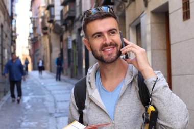 Eski şehir caddesinde telefonla konuşan yakışıklı bir gencin yakın plan portresi.