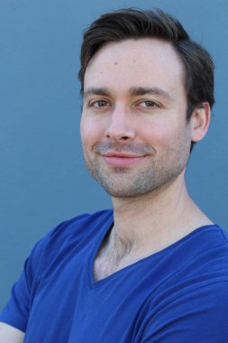 Mavi duvarın önünde sıradan giyinmiş yakışıklı bir gencin yakın plan portresi.