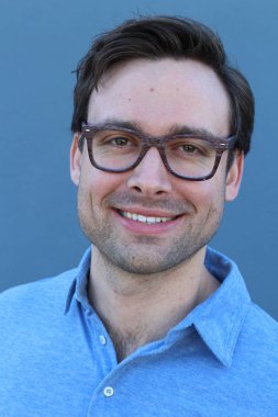 Mavi duvarın önünde sıradan giyinmiş yakışıklı bir gencin yakın plan portresi.