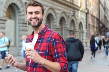 Sokakta elinde kağıt kahve olan yakışıklı bir gencin yakın plan portresi.