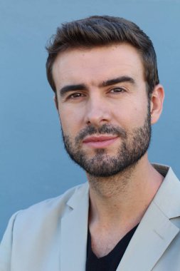 Duvarın önündeki yakışıklı sakallı adamın yakın plan portresi.