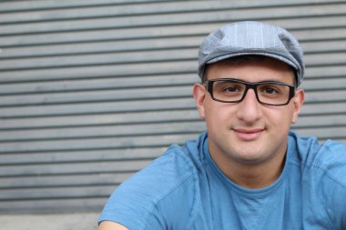 Gri duvarın önündeki mavi tişörtlü yakışıklı genç adamın yakın plan portresi.