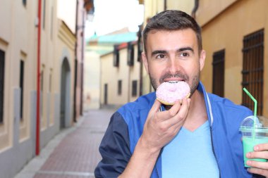 Donut yiyen ve dışarıda milkshake içen bir adam.