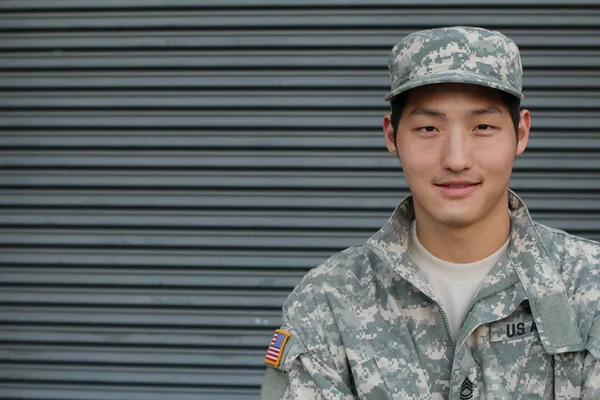 close-up portrait of handsome young asian us army soldier in front of wall