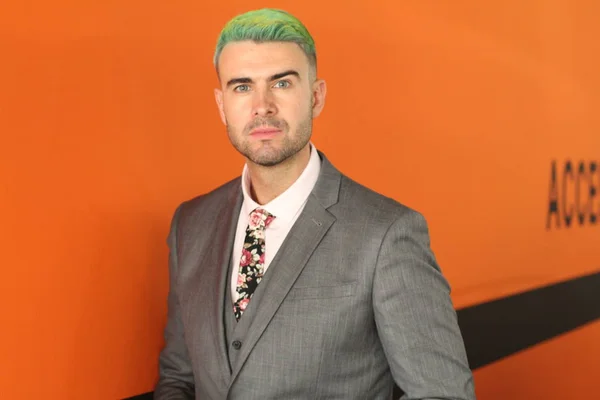 エレガントなハンサムな男で緑の髪立っているオレンジの背景 — ストック写真